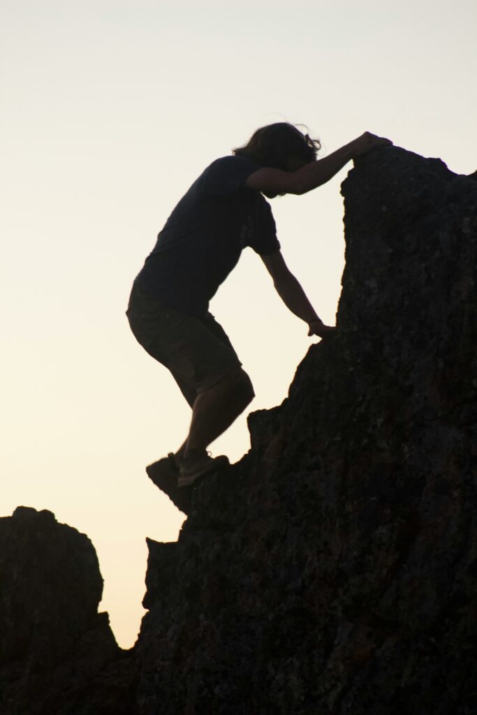 homme grimpant sur la roche en contrejour